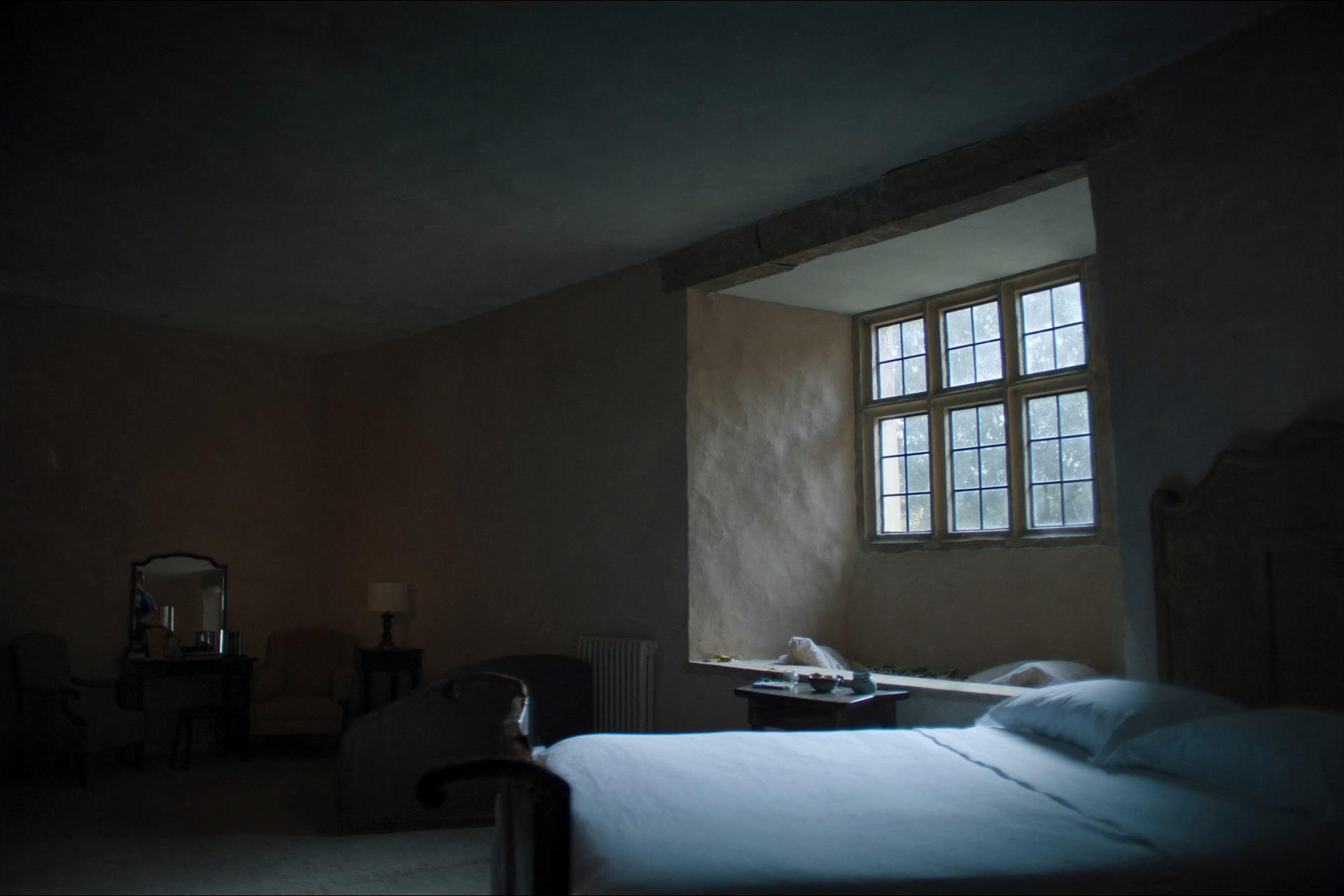 A guest bedroom with white linen and a deep stone window seat