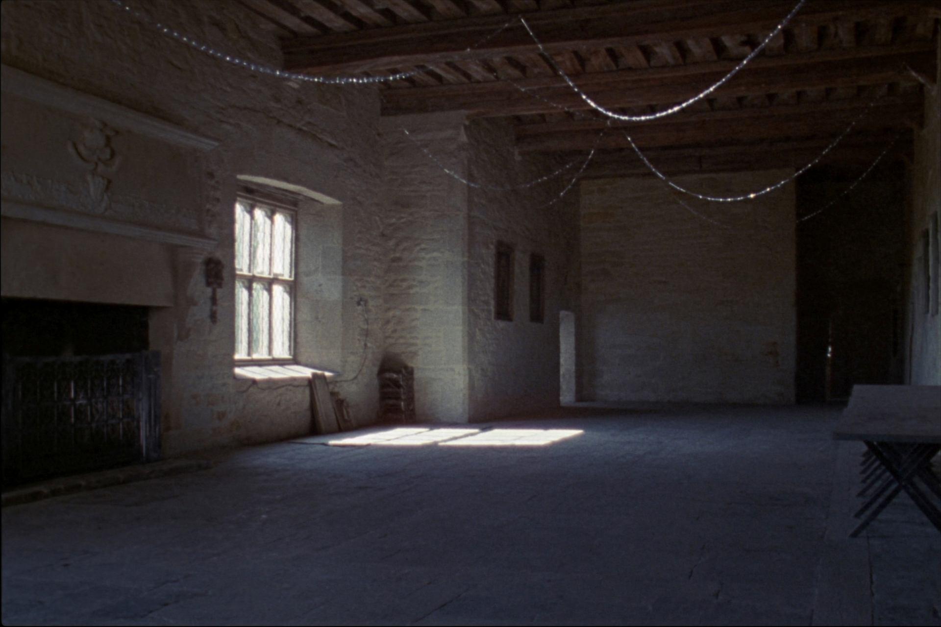 The great hall, empty, with bare stone walls and an oak beamed ceiling
